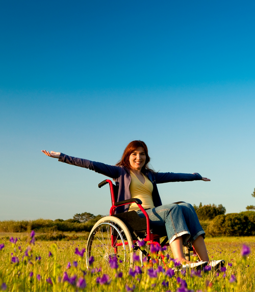 Lady sat amongst flowers in a self propelled red wheelchair.
